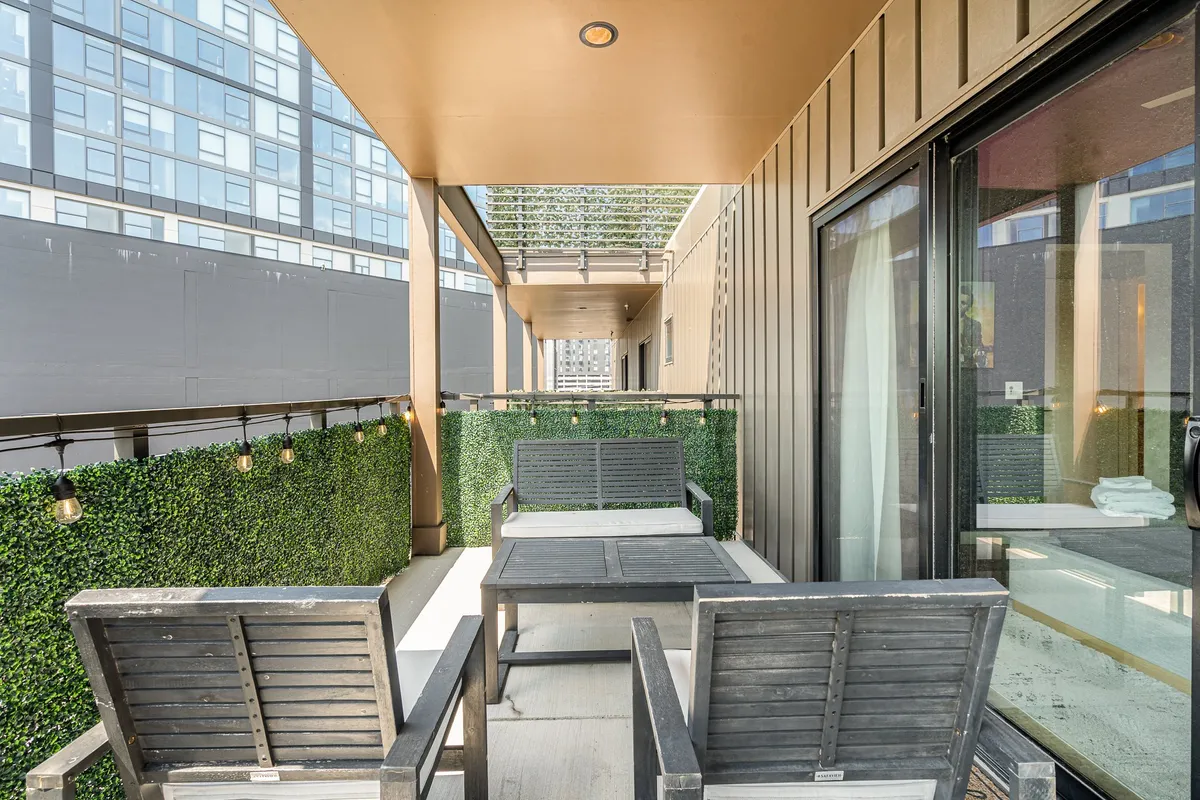 An inviting outdoor patio area with stylish furniture, lush greenery in planters, and soft lighting fixtures that create a serene ambiance for both day and night gatherings.