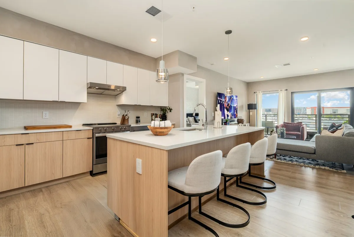 This photo spotlights a modern kitchen with a prominent island, ample seating area, large windows spilling sunlight into the space, and high-end appliances. The warm atmosphere suggests both culinary creativity and casual entertaining, tying into the chef's dream kitchen described in the text.