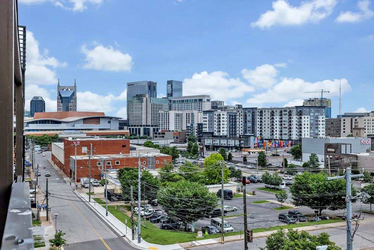 A panoramic view of the Nashville city skyline with modern buildings, open green spaces, and active roads, evoking the energy and accessibility of urban exploration. The vibrant cityscape highlights the proximity to top attractions and the lively feel of the SOBRO district.